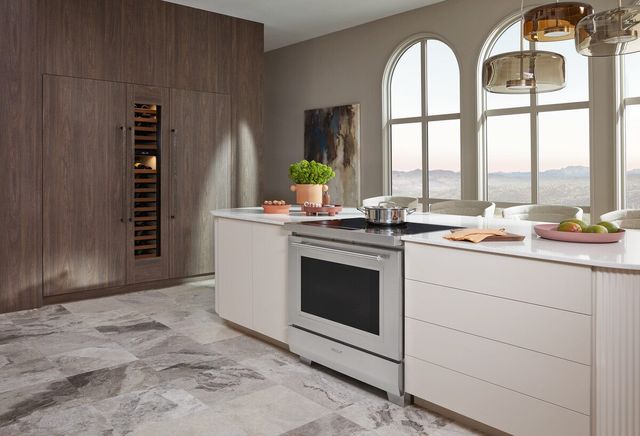 view of a modern luxurious kitchen with a 36" wolf induction range in an island in front of panel ready refrigeration