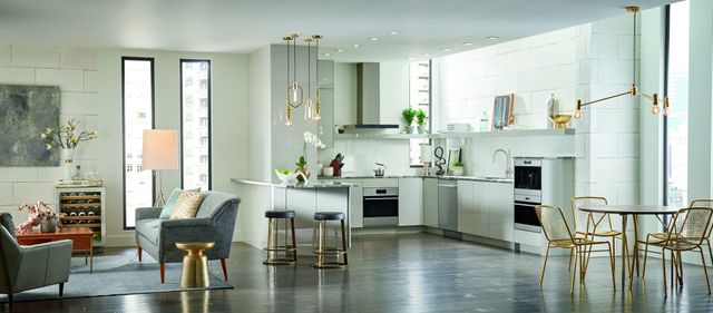 front view of a modern open concept living room and kitchen with Wolf wall ovens built into the cabinetry