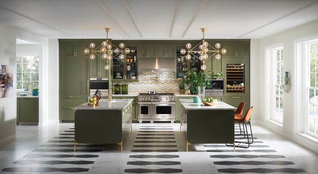 Front view of a modern luxury kitchen with white walls, green cabinetry, and luxury appliances.