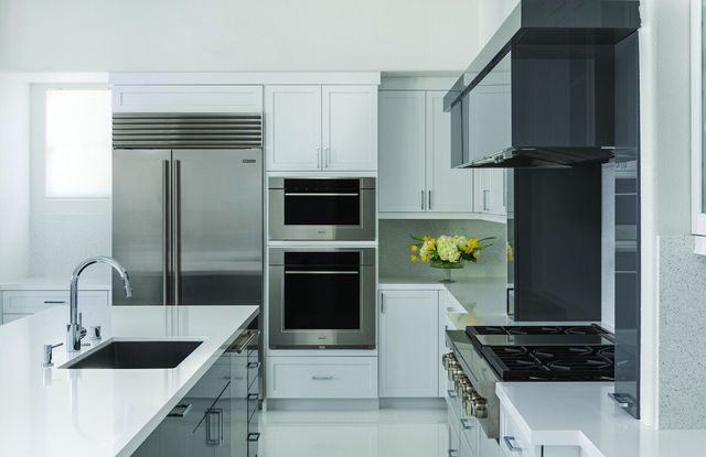Front view of a small kitchen with commercial grade appliances and an island with a sink.