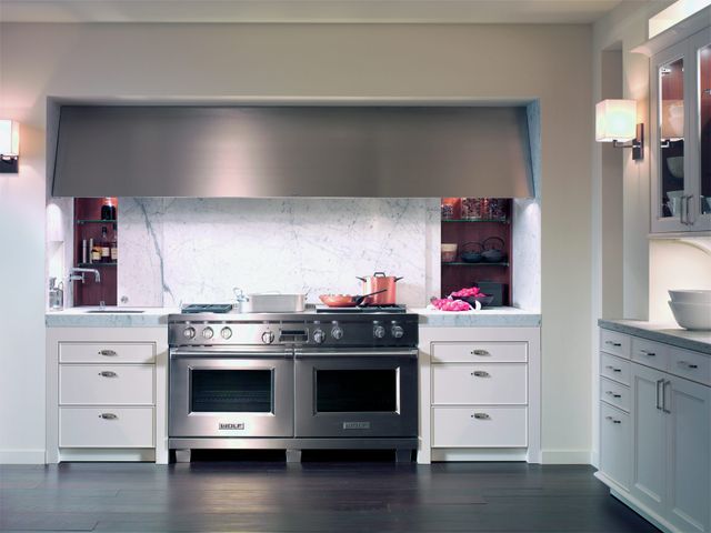 Front view of a Wolf double oven range with a large range hood in a luxury kitchen space
