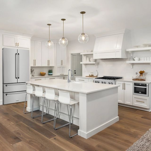 front view of a modern white kitchen with an island in the center and stainless steel zline appliances throughout