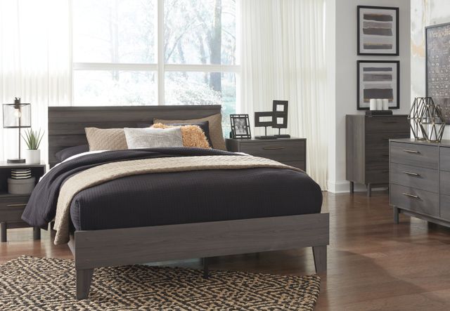 View of a modern bedroom with a grey full size bed set from Ashley Furniture and a large window on the wall.