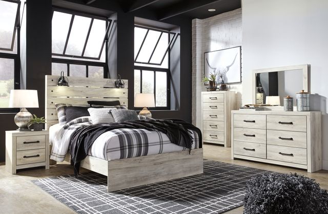 front view of a white wooden modern farmhouse bedroom set in a bedroom with white brick and black walls
