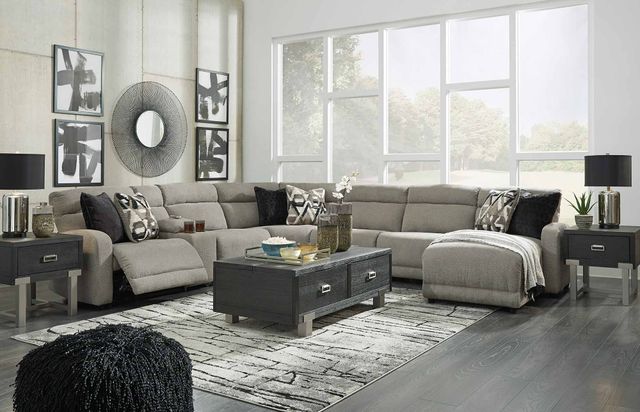 front view of a contemporary living room with a grey reclining sectional and in the background are large windows and various black and white decor.
