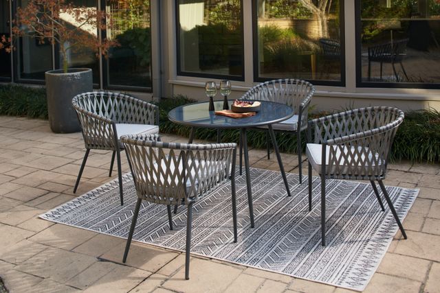 Front view of a modern outdoor patio with a metal and fabric table and chairs