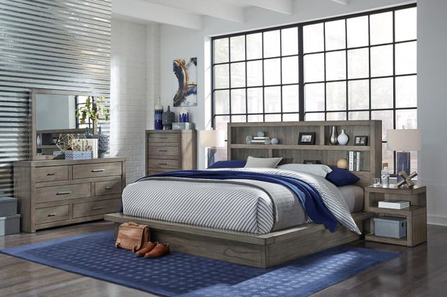 front view of a modern bedroom with white and grey walls, large windows, and a grey wooden queen furniture bed set with a bed, a nightstand, a dresser, and a chest