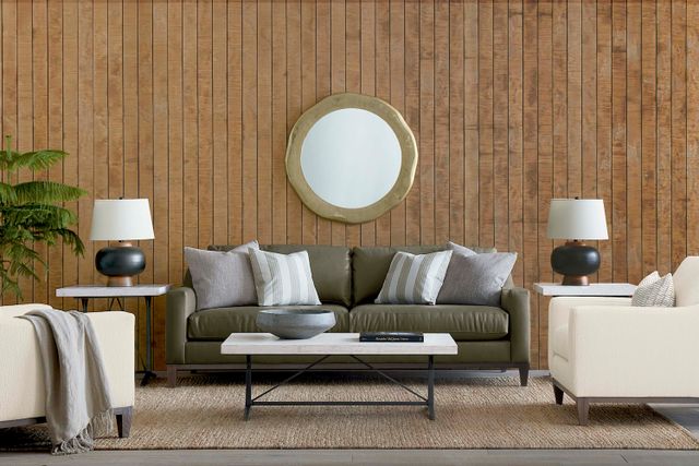 front view of a modern living room with a green sofa, brown wooden walls, and white and gold accents