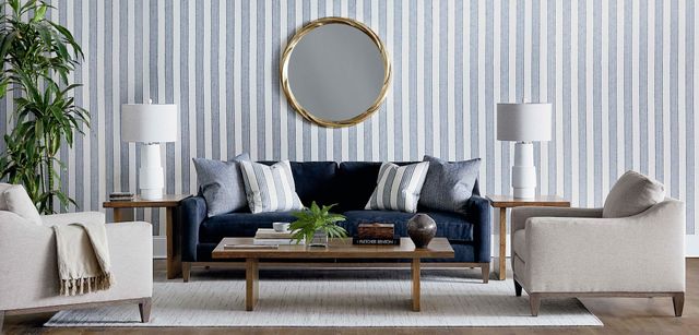 front view of a casual style living room with a blue sofa, striped walls, and various decor around the sofa