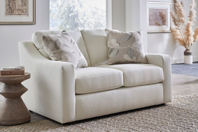 Modern living room with a large window letting light in with a white loveseat. 