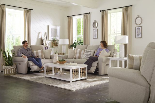 front view of two people sitting on a beige catnapper sofa and loveseat reclined out in a modern living room