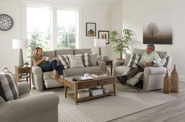 front view of a casual living room with catnapper reclining sofas and one person sitting and smiling on each