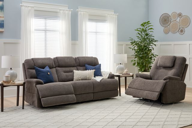 Front view of a modern living room with a light blue wall and a matching grey sofa and recliner