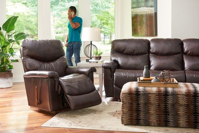 Front view of a modern living room with a matching sofa and loveseat and a man on the phone in the background
