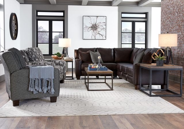 front view of a modern living room with a leather sectional and a textile accent chair with a throw