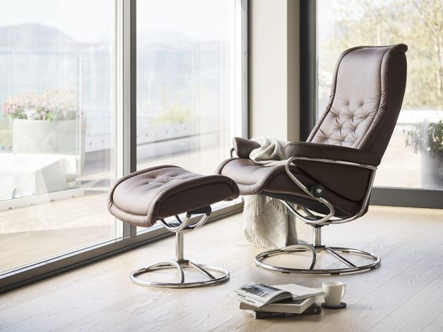 front view of a brown stressless chair in front of a large window