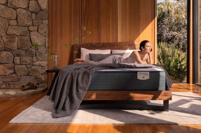 Front view of a casual bedroom with a woman smiling and laying on a platform bed.