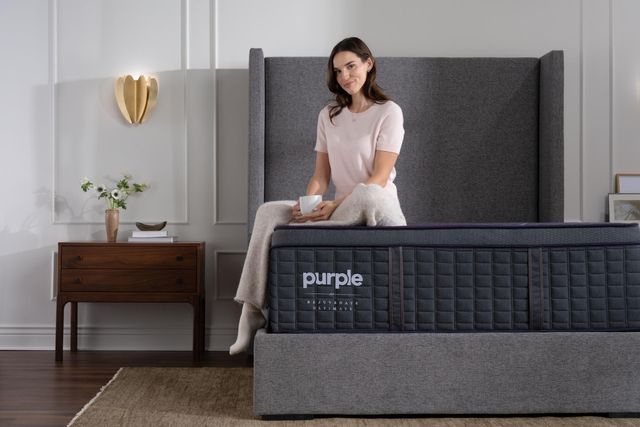 Front view of a woman sitting and smiling on a Purple mattress