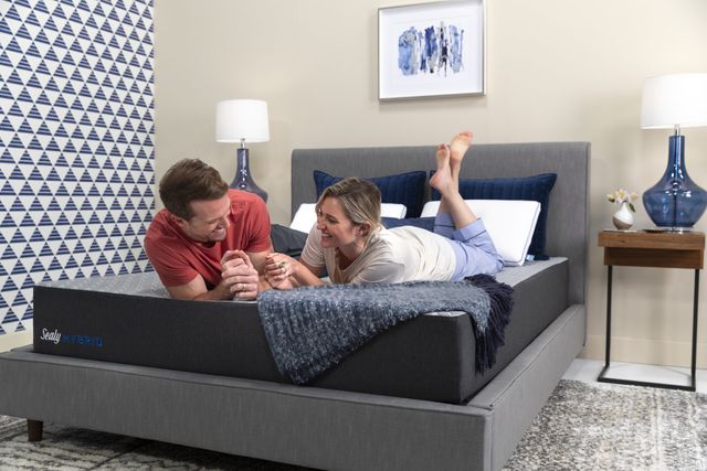 front view of a man and woman smiling on a sealy mattress