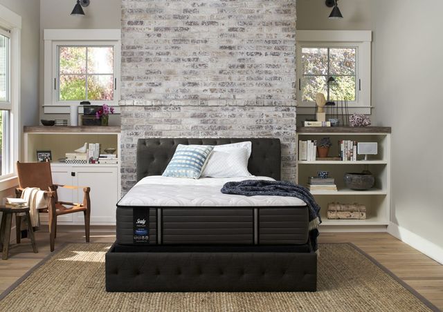 front view of  a modern rustic bedroom with a pillow top mattress on a black bed frame in front of a white brick wall