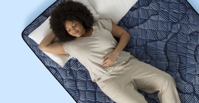 top view of a woman laying on a sealy mattress with her eyes closed smiling