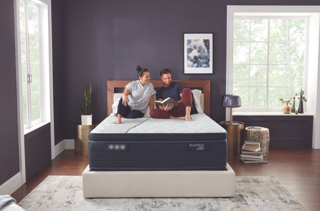 front view of a couple sitting on a Serta mattress 