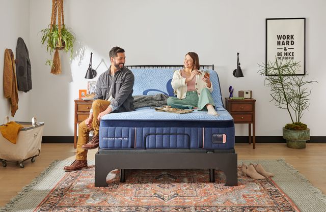 front view of a couple sitting on a stearns and foster hybrid mattress