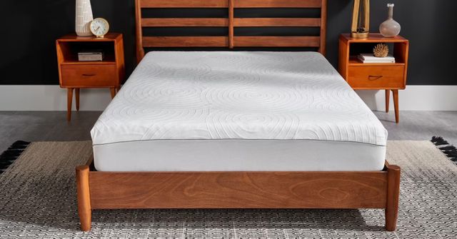 Front view of a Tempur-Pedic mattress with protector on a platform bed in a modern bedroom setup.