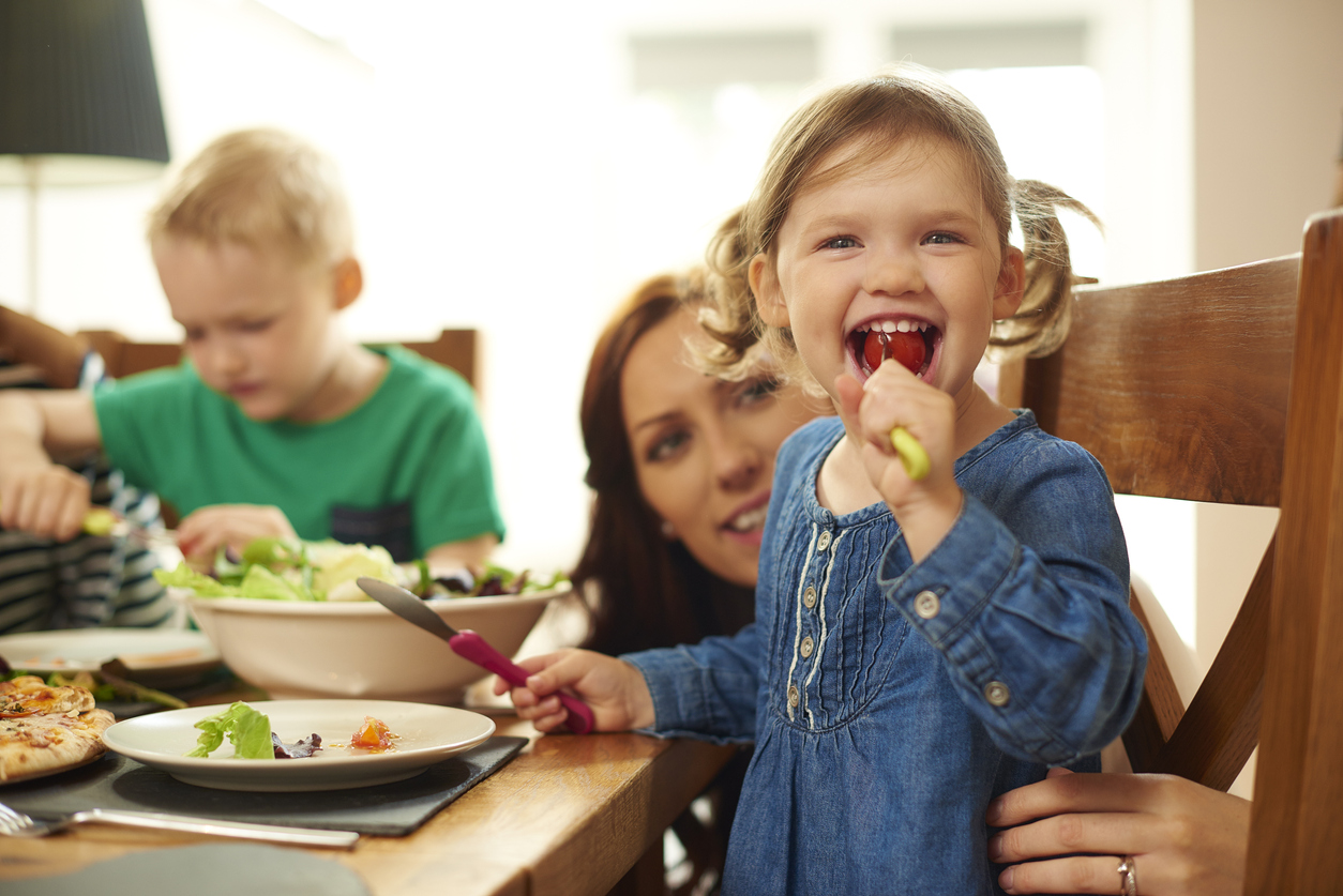 A young girl sits at a dining room table with her family