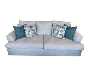 front view of a soft light gray sofa with two teal pillows and two patterned team and gray pillows