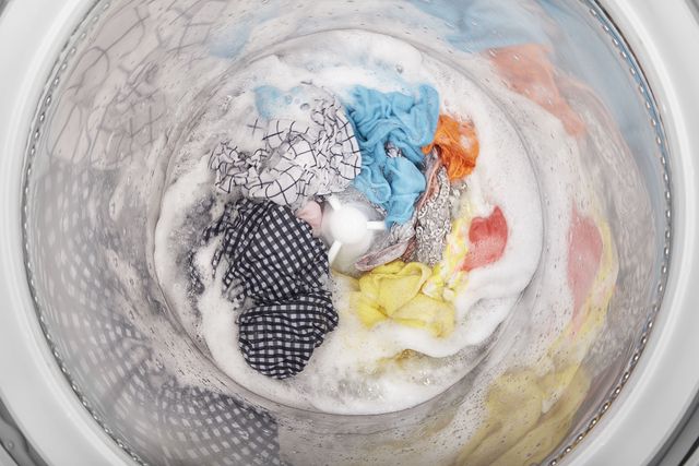 top view of a top load washer bucket with soap and clothes spinning inside