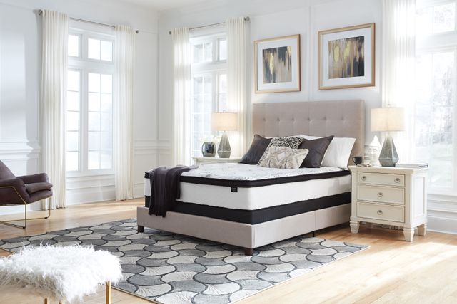 front view of a modern bedroom with white walls, grey accents, and a Sierra Sleep mattress from a box on the bed