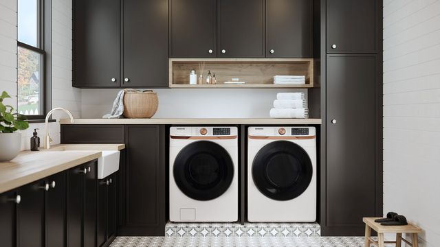 view of a white samsung washer and dryer in a modern laundry room with white walls and black cabinets