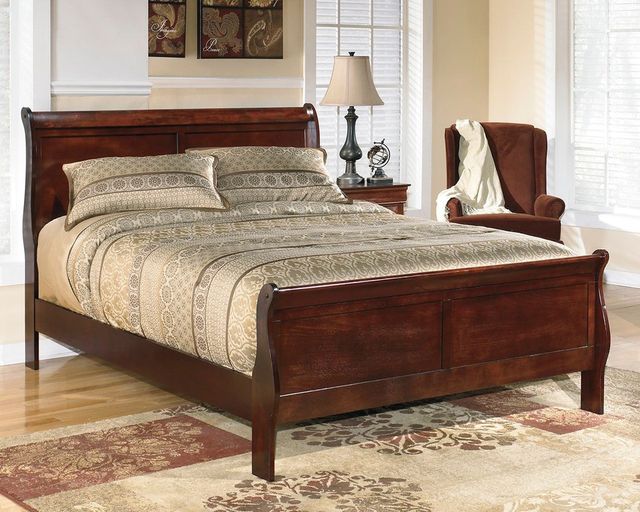 Darkly-stained wooden sleigh bed in a bedroom with light yellow walls