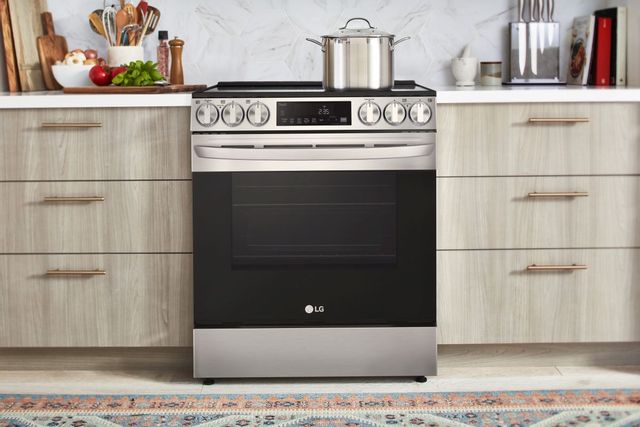 front view of an LG electric range in a modern kitchen with light wood cabinets and marble backsplash