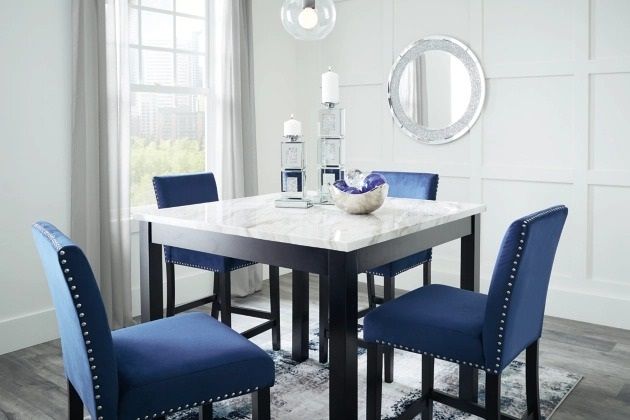 front view of a square marble dining table with blue upholstered seating and glam accents throughout