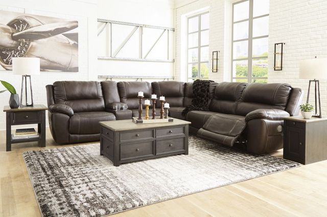 front view of the Signature Design by Ashley® Dunleith 7-Piece Chocolate Power Reclining Sectional, styled in a transitional living room with white walls and dark brown furniture