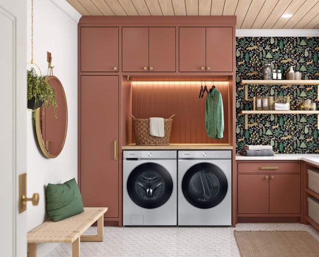 front view of a modern laundry room with peach cabinets, grey samsung washer and dryer, and green accents