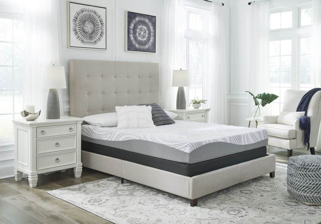 traditional memory foam mattress on a grey bed frame in a modern bedroom, with four pillows stacked on top