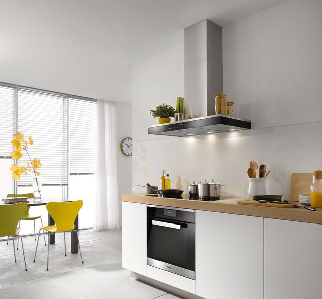 front view of a modern white kitchen with ventilation and a range below