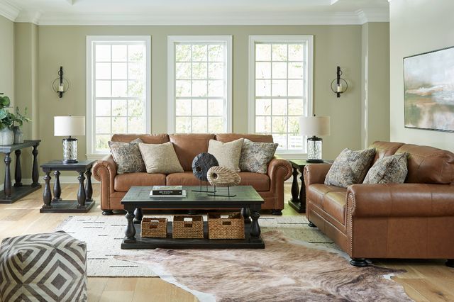 front view of a modern living room with a medium brown leather sofa and loveseat around a black coffee table