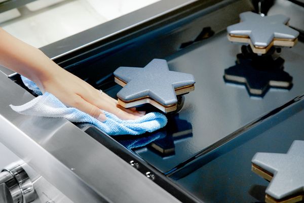 hand reaching into thermador range with rag to clean