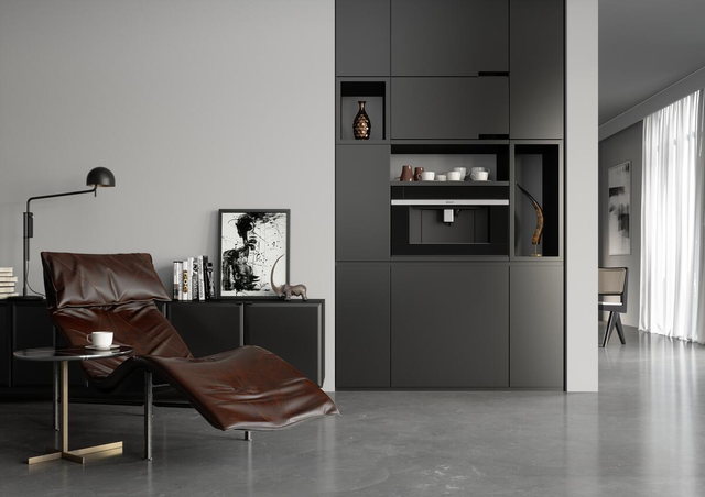 wolf built in coffee maker in a coffee bar storage wall in a modern grey home with a brown chair to the left, styled