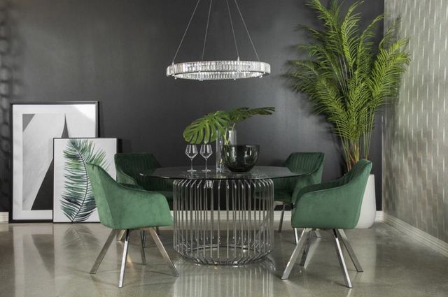 round glass dining table with green chairs around it in a stylish, dark dining room
