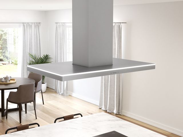 front view of an island range hood installed in a modern home with white walls and decot