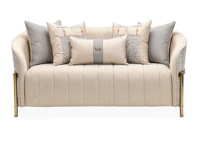front view of a cream colored round sofa with five cream colored and gray pillows