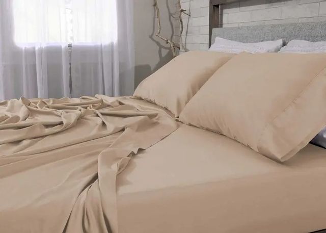 close view of coral colored sheets and pillowcases on a bed in a rustic bedroom