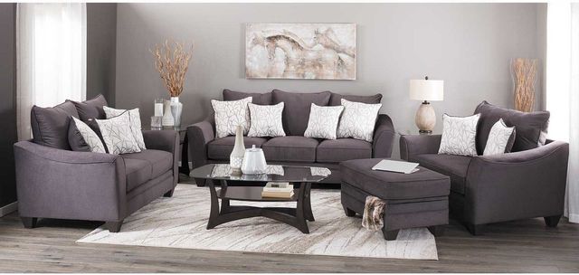 front view of a modern living room with gray walls, and gray wood floors. In the room is a dark gray modern sofa, loveseat, and chair, all surrounding a black and glass coffee table. White pillows sit on top of each couch.