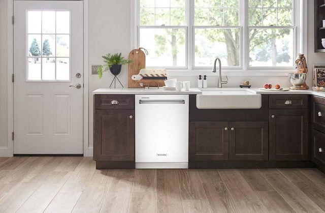 front view of a modern kitchen with a white kitchenaid dishwasher built into brown cabinetry