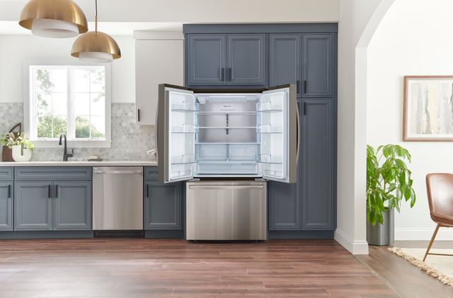 front view of a modern kitchen with blue cabinets and a stainless steel french door counter depth refrigerator